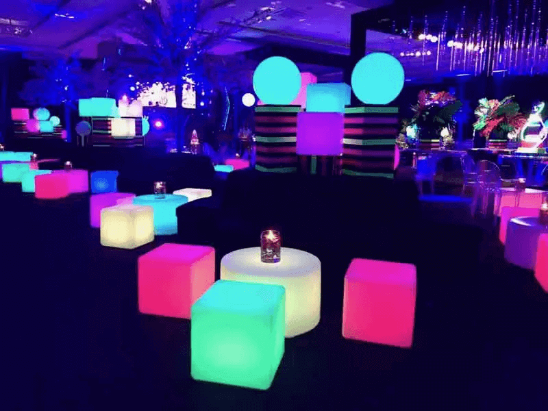 Puff para festas e eventos: lounge elegante com puffs de cores neutras ao redor de uma mesa de centro decorada com arranjos florais.